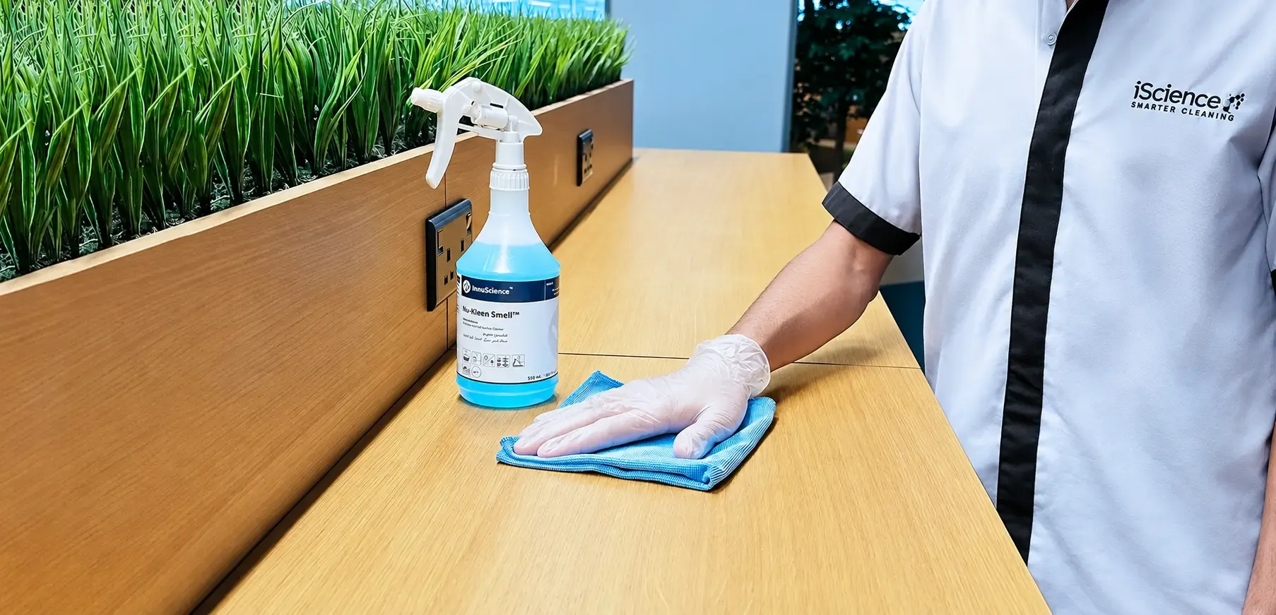 An iScience cleaner wiping a desk with an eco-friendly product
